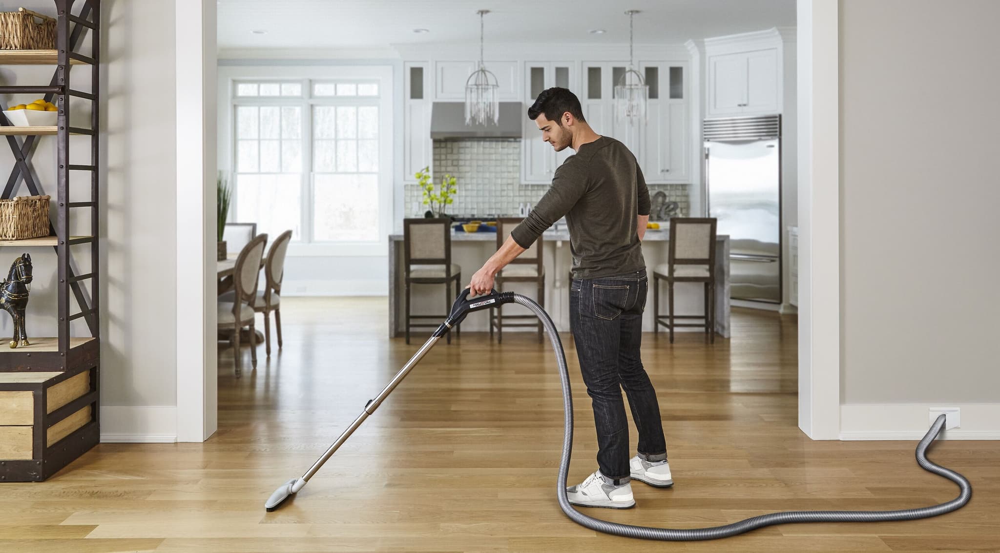 Man vacuuming modern kitchen with HausVac central vacuum